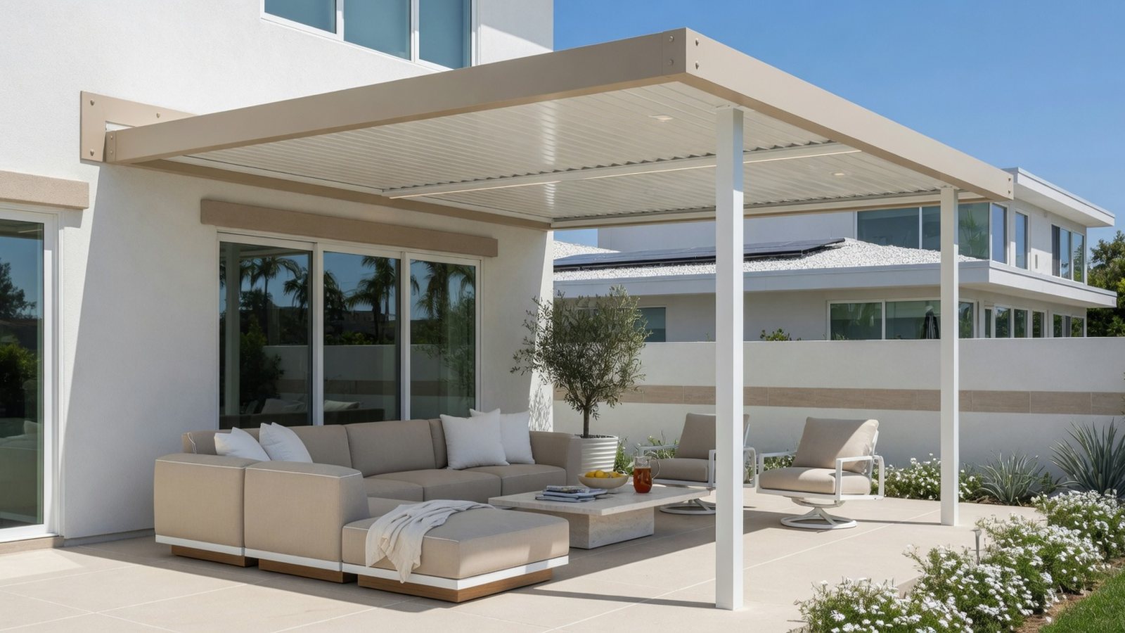 Attached patio cover shading lounge seating beside a light stucco Southern California home